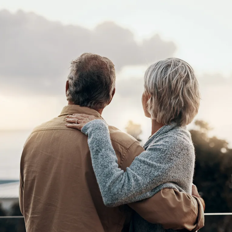 An elderly couple stands outdoors